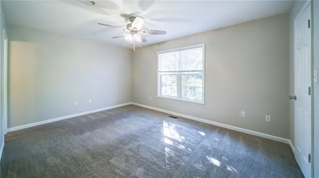 an empty room with windows and chandelier fan