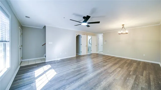 a view of empty room with wooden floor and fan