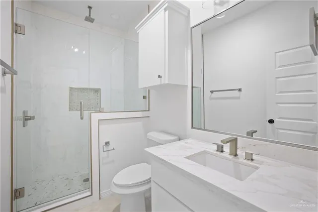 a bathroom with a granite countertop sink a toilet and shower