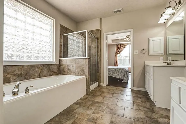 a spacious bathroom with a tub sink and a mirror