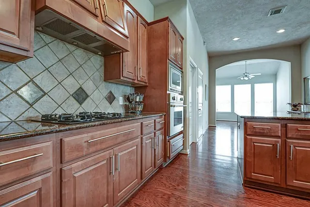 a kitchen with stainless steel appliances granite countertop a refrigerator a sink dishwasher and wooden cabinets with wooden floor