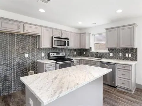 a kitchen with granite countertop a sink stainless steel appliances and white cabinets