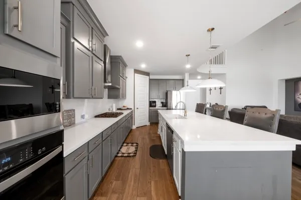 a large kitchen with stainless steel appliances a stove a sink a microwave and cabinets