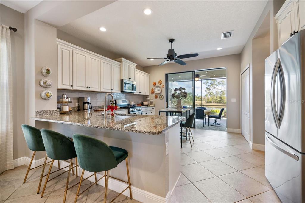 208 Brienza Loop Nokomis, FL 34275 - Photo 8 of 45 a kitchen with stainless steel appliances granite countertop a refrigerator a sink a stove and white cabinets with wooden floor