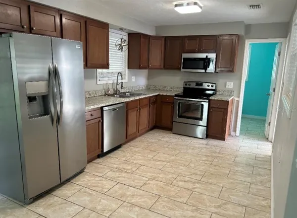 a kitchen with stainless steel appliances granite countertop a refrigerator a stove a sink and a microwave