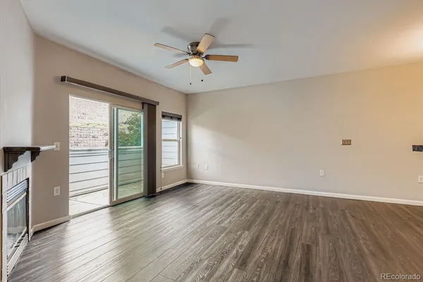 an empty room with wooden floor fan and windows