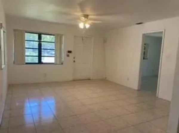 an empty room with windows and fan