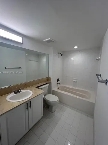 a bathroom with a granite countertop sink a toilet a mirror and bathtub