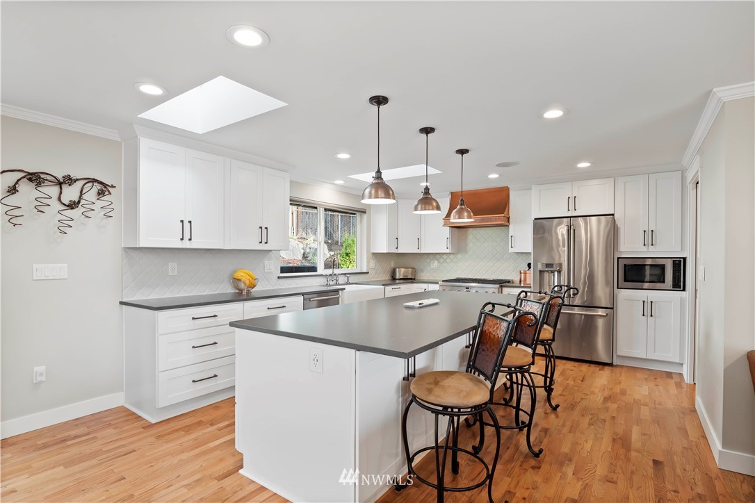 10404 Northeast 197th Street Bothell, WA 98011 - Photo 11 of 29 a kitchen with stainless steel appliances granite countertop a sink a stove a refrigerator and island with wooden floor