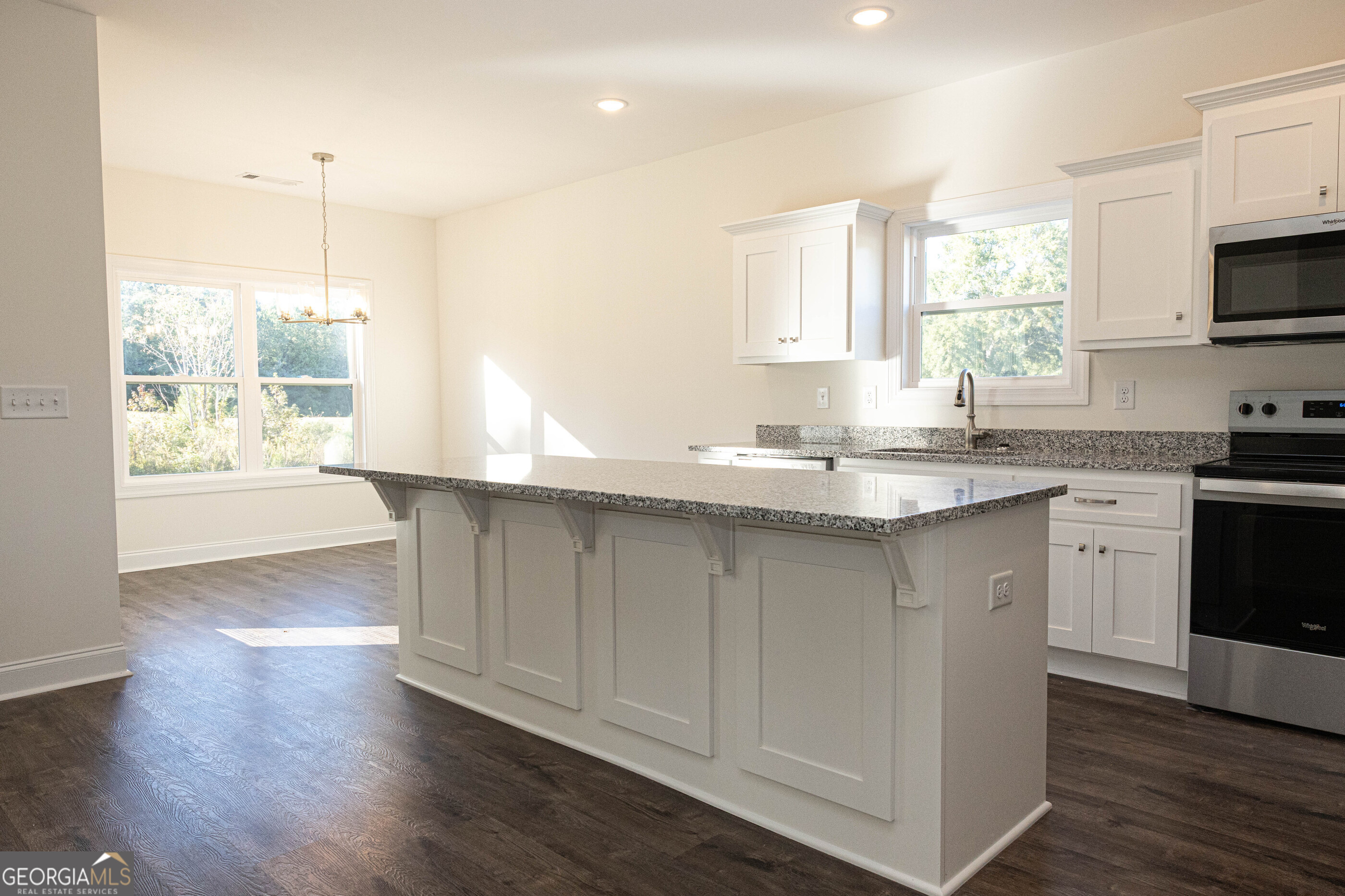 705 Riverside Estates Lanett, AL 36863 - Photo 10 of 29 a kitchen with granite countertop a stove a sink and white cabinets with wooden floor