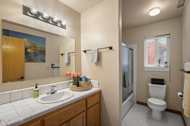 a bathroom with a granite countertop sink toilet a mirror and shower