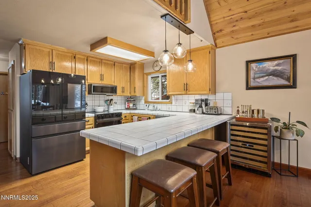 a kitchen with stainless steel appliances granite countertop a table chairs and a refrigerator