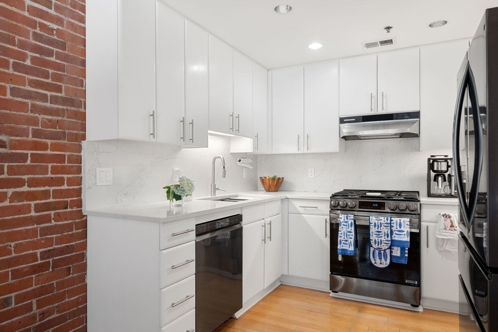 9 West Broadway, Unit 314 Boston, MA 02127 - Photo 13 of 25 a kitchen with stainless steel appliances granite countertop a sink a stove a refrigerator and white cabinets