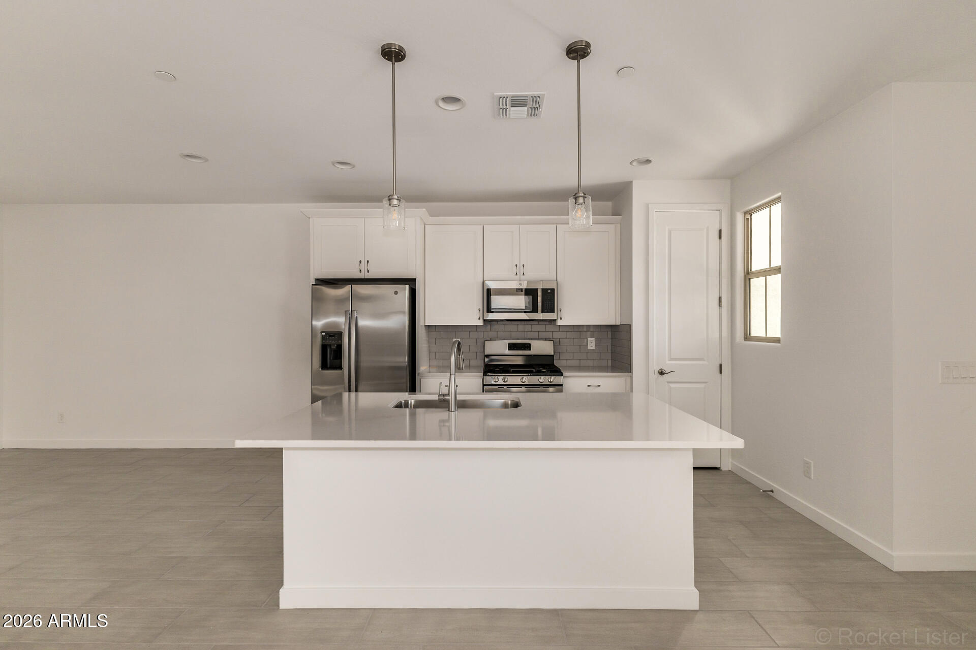 20618 West Thomas Road Buckeye, AZ 85396 - Photo 7 of 38 a kitchen with kitchen island a counter top a stove a sink a refrigerator and a window