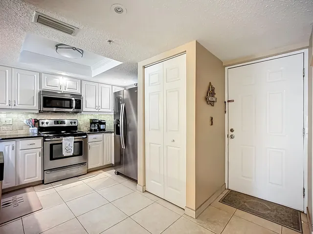 a kitchen with stainless steel appliances granite countertop a refrigerator sink and white cabinets