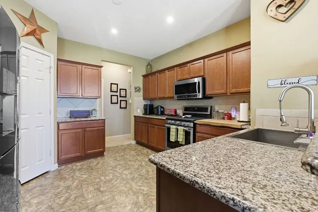 a kitchen with stainless steel appliances granite countertop a sink stove and refrigerator