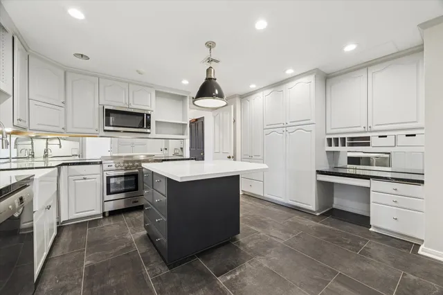 a kitchen with kitchen island granite countertop a sink counter top space appliances and cabinets
