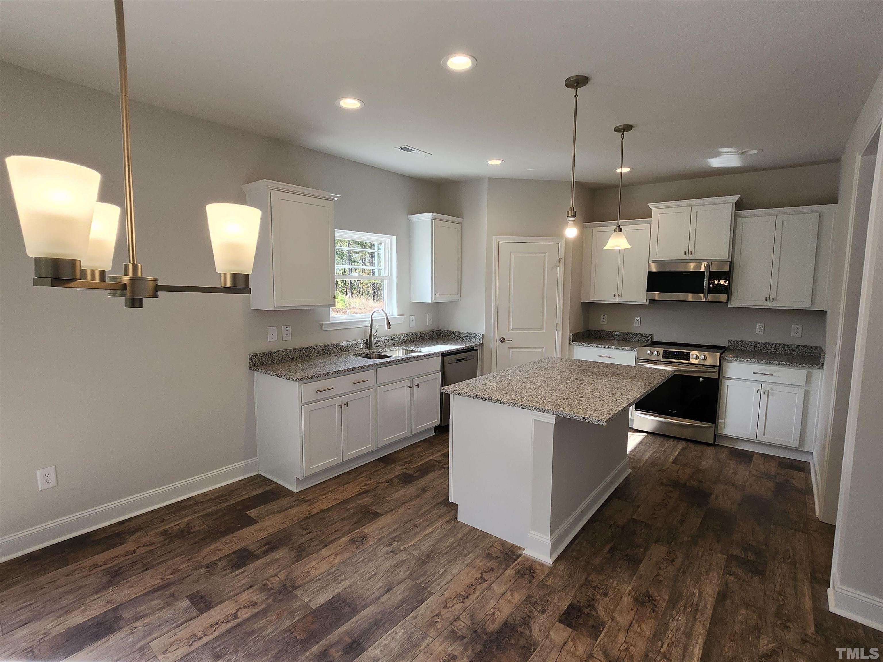 243 Spring Flowers Drive Cameron, NC 28326 - Photo 5 of 30 a kitchen with stainless steel appliances kitchen island a sink a stove a microwave a center island and a window