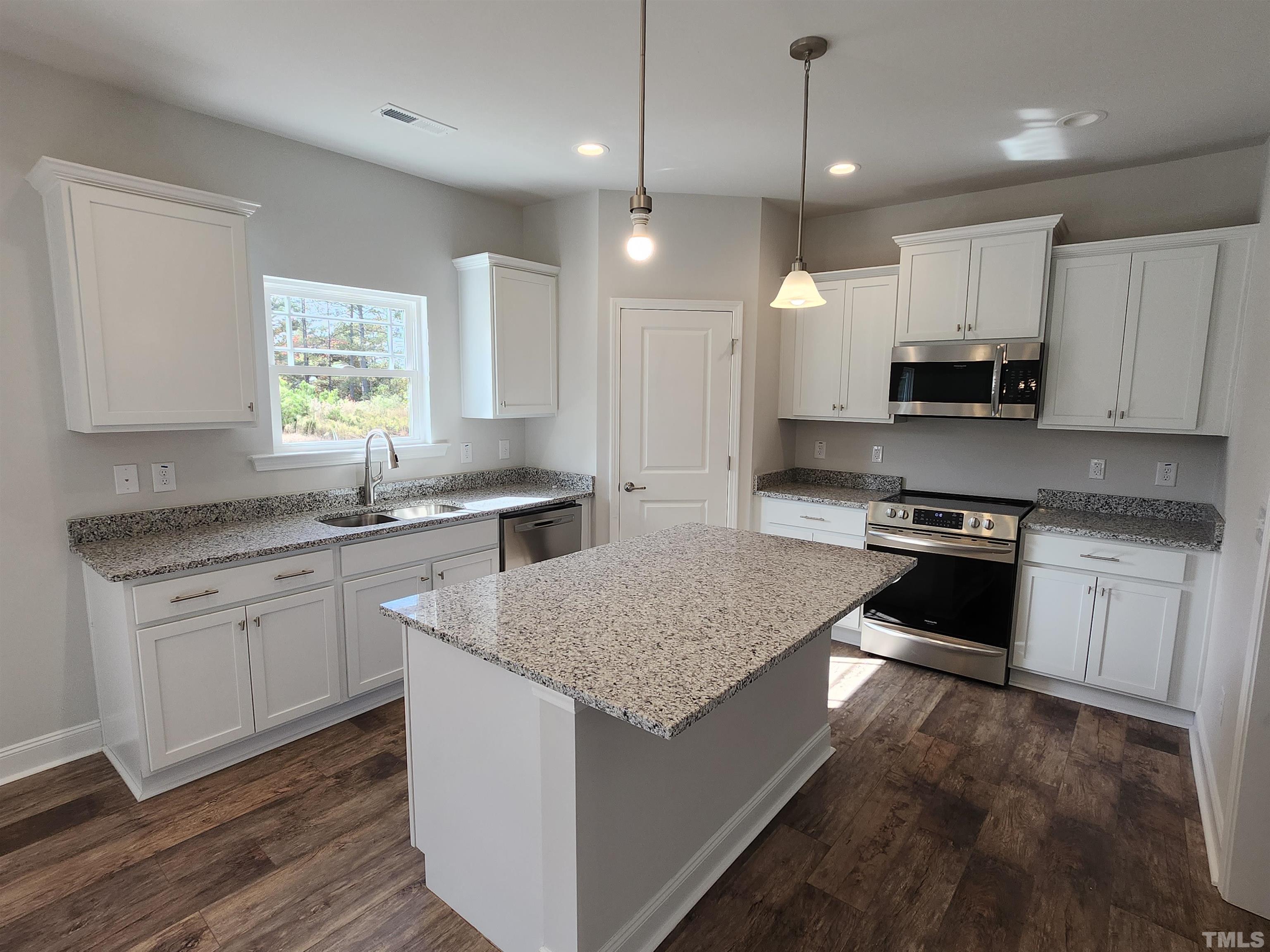 243 Spring Flowers Drive Cameron, NC 28326 - Photo 7 of 30 a kitchen with a stove a sink a kitchen island with wooden cabinets and floor