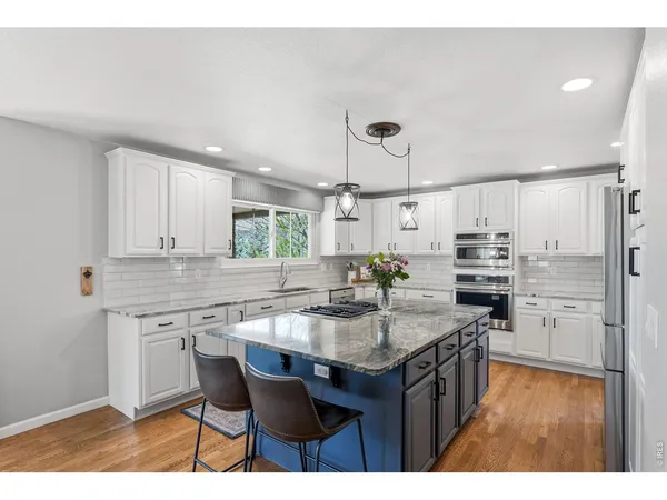a open kitchen with stainless steel appliances kitchen island granite countertop a table chairs and a refrigerator