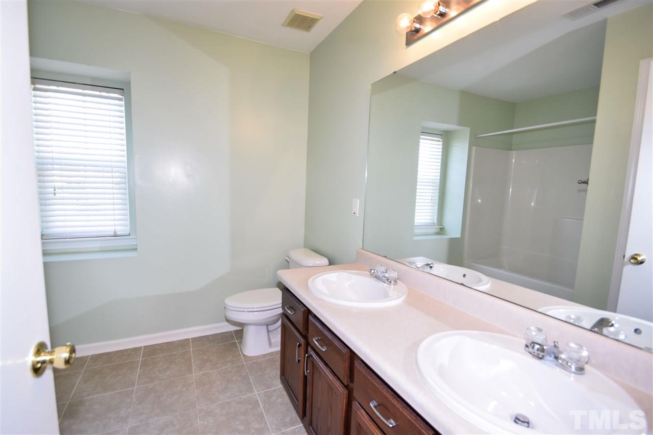 6134 Ricker Road Raleigh, NC 27610 - Photo 22 of 30 a bathroom with a double vanity sink toilet and a mirror