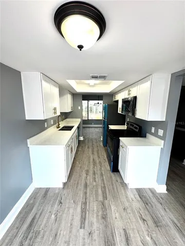 a large kitchen with kitchen island a stove top oven a sink a counter space and wooden floor