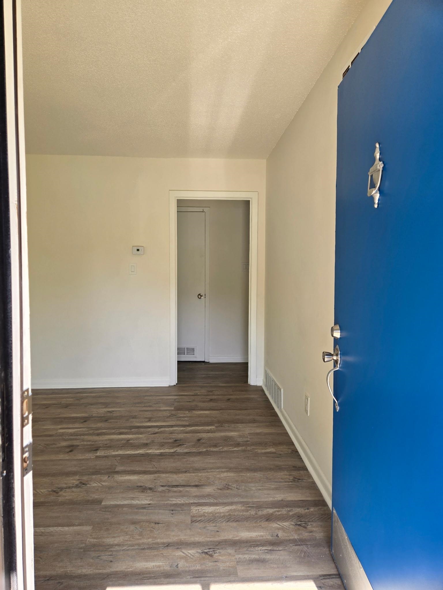 2889 Randy Cove Memphis, TN 38118 - Photo 6 of 18 Entryway featuring a vibrant blue front door with polished silver hardware, wood-finish flooring, white baseboards, and a neutral wall palette