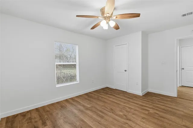 a view of empty room with wooden floor and fan