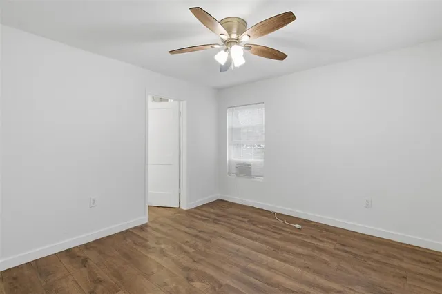 an empty room with a window and a fan