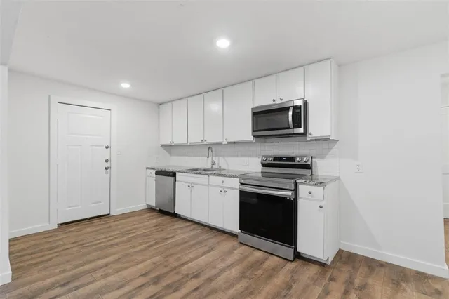a kitchen with granite countertop a stove top oven sink and cabinets