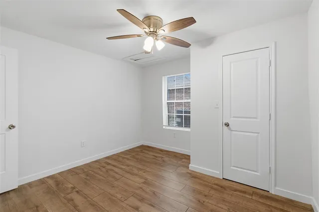 an empty room with wooden floor closet and windows