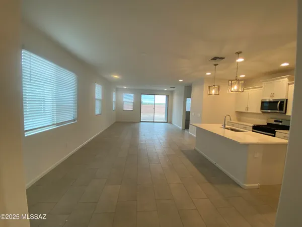 a view of a kitchen with kitchen island a sink wooden floor and a large window