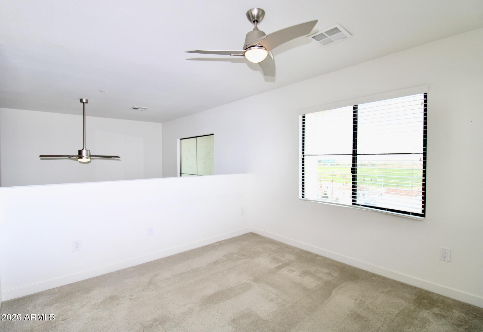 2511 West Queen Creek Road, Unit 438 Chandler, AZ 85248 - Photo 11 of 23 en empty room with windows and ceiling fan