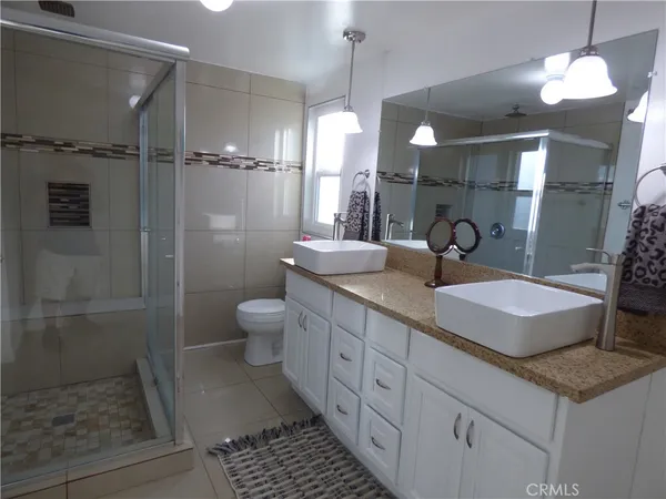 a bathroom with a granite countertop sink a toilet a mirror and shower