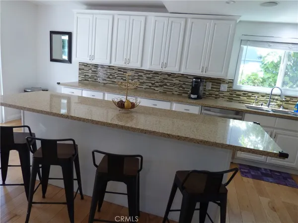 a kitchen with stainless steel appliances granite countertop a table chairs sink and cabinets