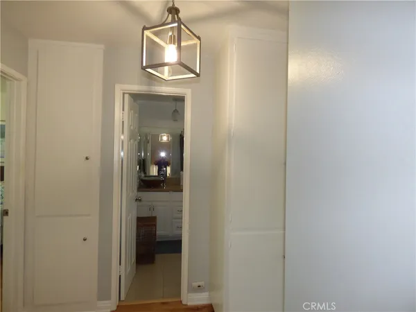 a view of a hallway with wooden floor and a bathroom