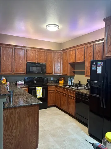 a kitchen with granite countertop a refrigerator stove top oven and sink