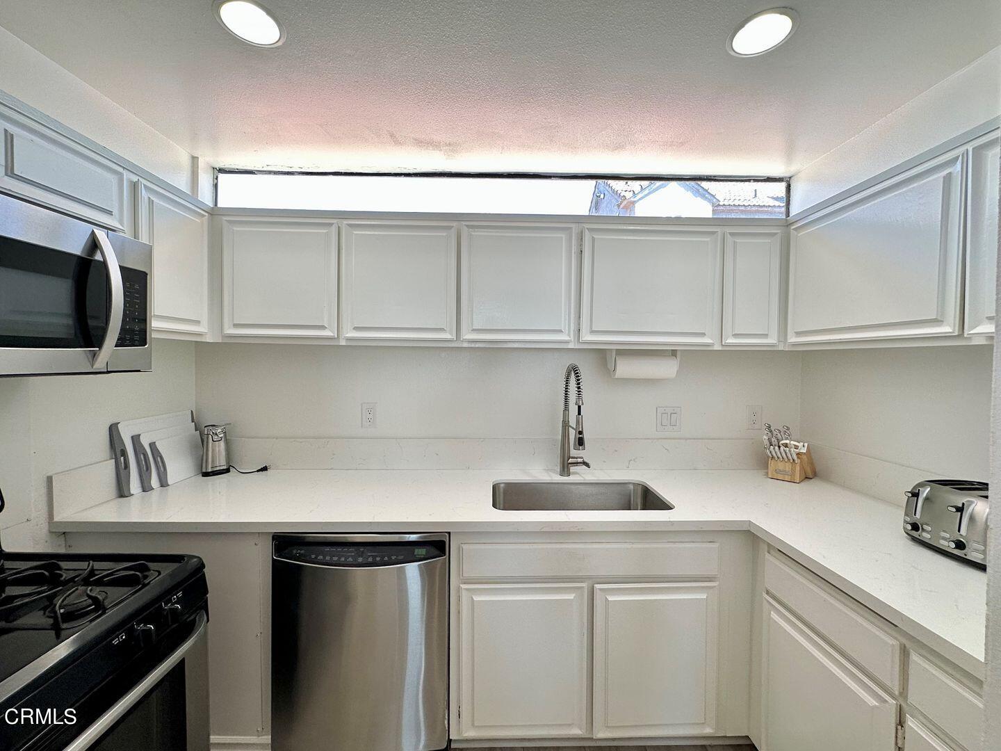 1364 Neptune Square Oxnard, CA 93035 - Photo 18 of 42 a kitchen with stainless steel appliances a sink dishwasher stove and cabinets with wooden floor