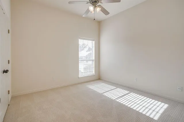an empty room with a chandelier fan and windows