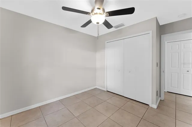 an empty room with a ceiling fan and carpet