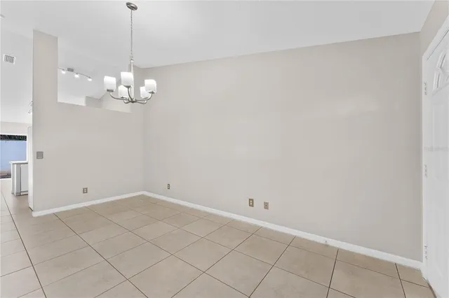 a view of an empty room with chandelier fan