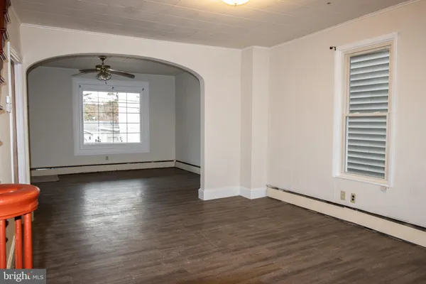 an empty room with wooden floor chandelier and windows