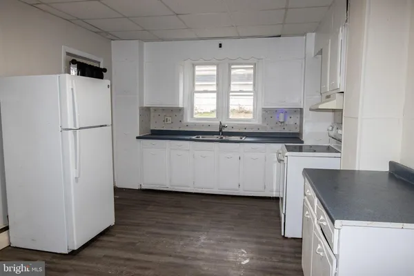 a kitchen with stainless steel appliances granite countertop a sink a stove a refrigerator with white cabinets and wooden floor