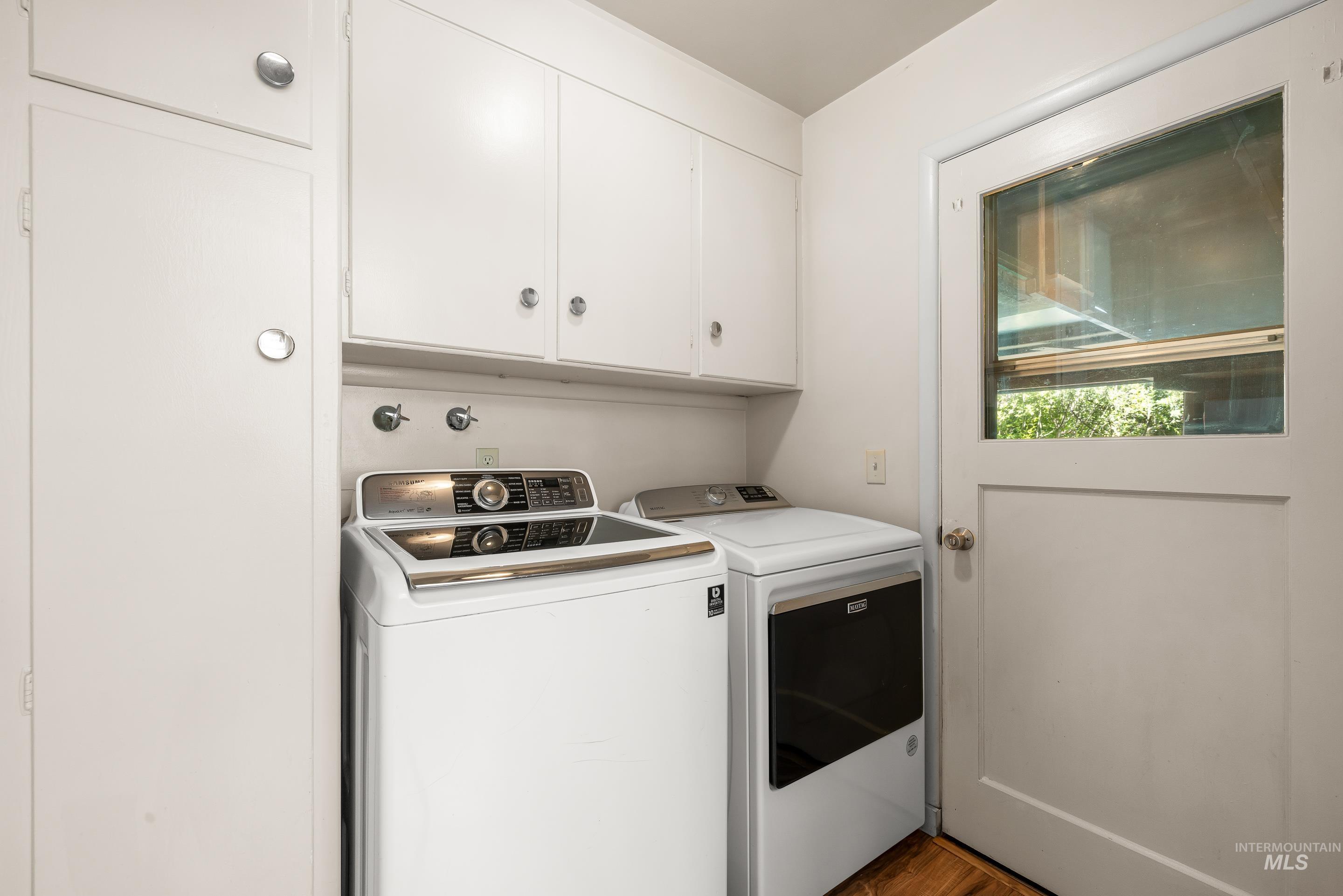 708 South Phillippi Street Boise, ID 83705 - Photo 20 of 25 Laundry area featuring wood-finish flooring, white cabinetry with silver-tone hardware, and a white paneled door with an upper window