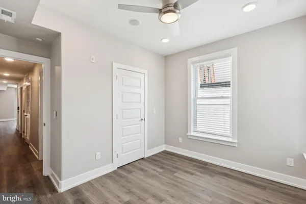 an empty room with wooden floor cabinet and windows