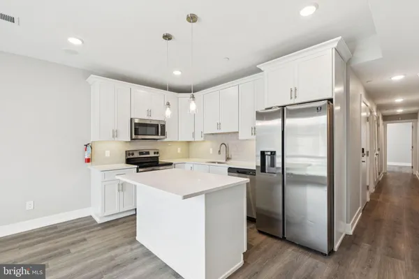a kitchen with stainless steel appliances a refrigerator a stove a sink and white cabinets