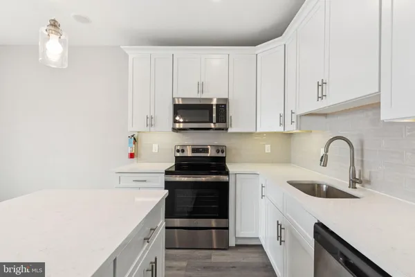 a kitchen with white cabinets and black appliances