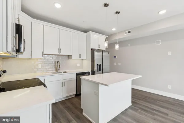 a kitchen with a sink a stove a refrigerator and white cabinets