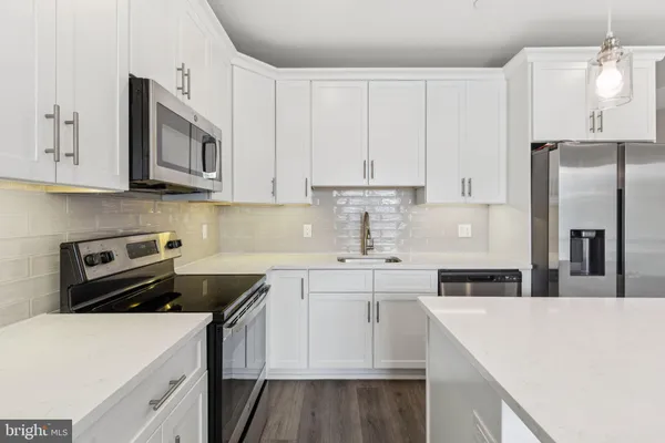 a kitchen with stainless steel appliances a stove a sink a refrigerator and white cabinets