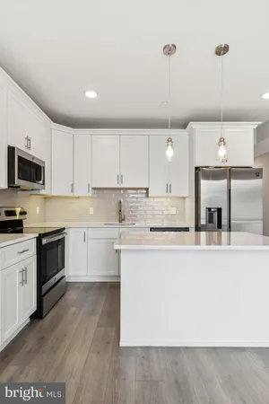 a large kitchen with granite countertop a stove a sink a center island and stainless steel appliances